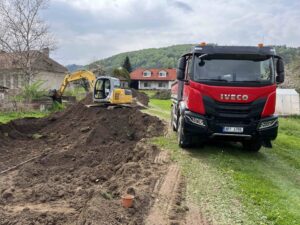 Nákladní auto Iveco a bagr na hromadě hlíny